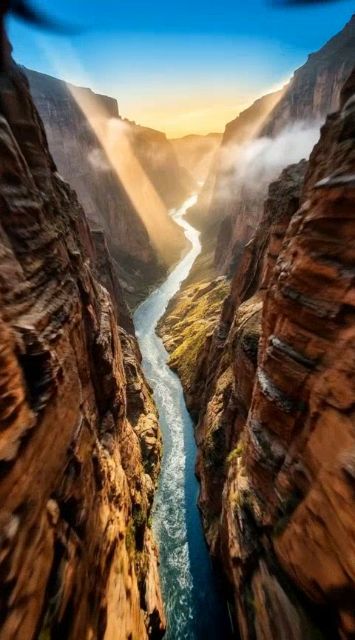 FPV drone shot, extreme speed. Flying incredibly fast through the narrow canyon. The walls rush past the camera rapidly. Diving down towards the river at high velocity.