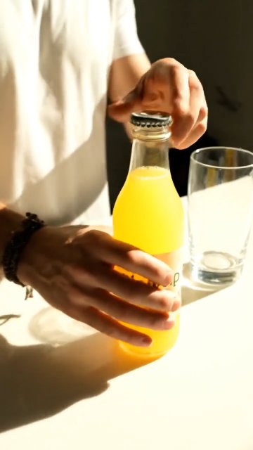 Create a 6-second vertical TikTok UGC ad. Product: GlowSip Electrolyte Drink (citrus). Goal: drive clicks to try a free sample. Style: handheld phone, authentic, bright kitchen lighting. Structure: 0-1s hook, 1-4s demo/benefit, 4-6s CTA. On-screen text captions only (no voiceover).